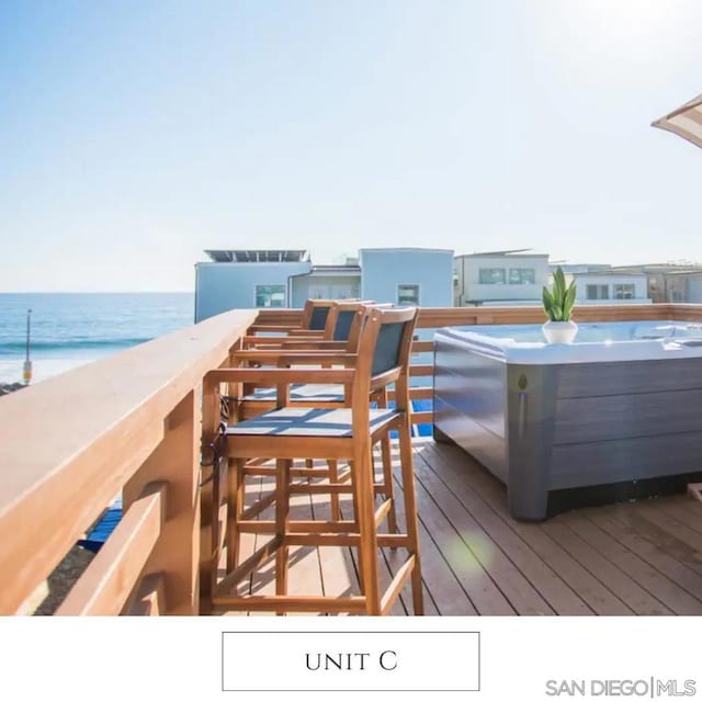 wooden terrace with a water view and a hot tub