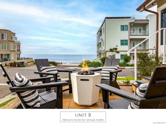 balcony featuring a deck with water view and an outdoor fire pit