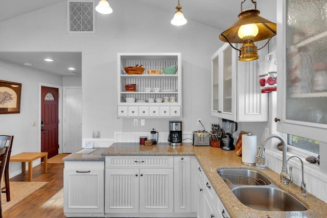 kitchen featuring sink, hanging light fixtures, hardwood / wood-style floors, lofted ceiling, and white cabinets