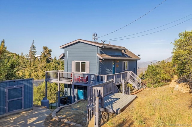 rear view of property with a storage shed and a wooden deck