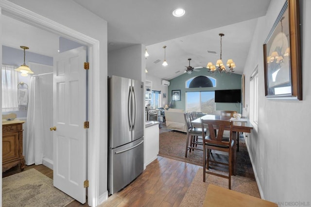 kitchen featuring pendant lighting, lofted ceiling, ceiling fan with notable chandelier, wood-type flooring, and stainless steel refrigerator