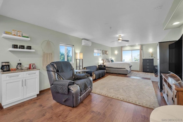 living room featuring a wall mounted air conditioner, hardwood / wood-style flooring, and ceiling fan