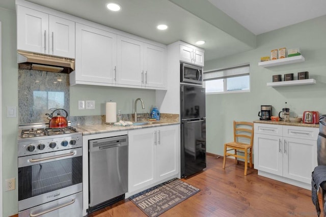 kitchen featuring sink, tasteful backsplash, white cabinets, exhaust hood, and appliances with stainless steel finishes