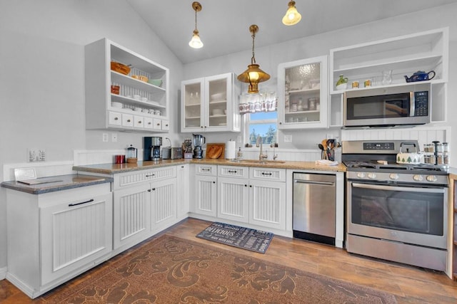 kitchen with lofted ceiling, white cabinets, hanging light fixtures, sink, and appliances with stainless steel finishes