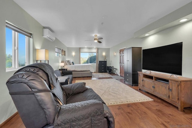 living room featuring a wall mounted air conditioner, ceiling fan, and light wood-type flooring