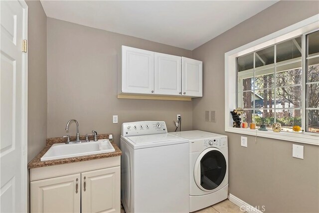 washroom with cabinets, light tile patterned floors, washing machine and dryer, and sink