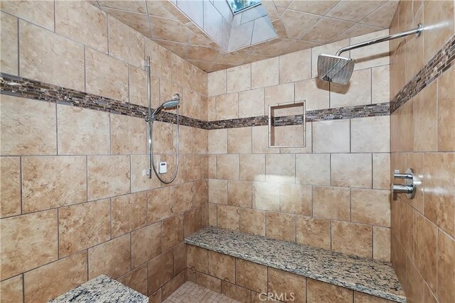 bathroom featuring tiled shower and a skylight