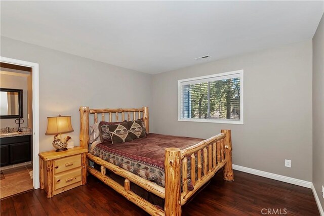 bedroom with connected bathroom, sink, and dark wood-type flooring