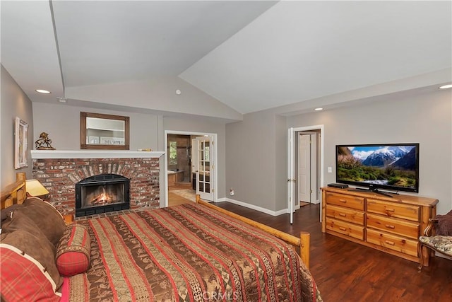 bedroom featuring a brick fireplace, dark wood-type flooring, and lofted ceiling