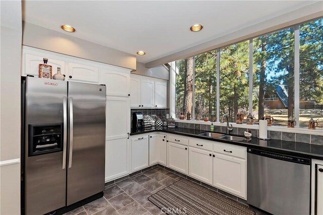 kitchen with decorative backsplash, sink, white cabinetry, and stainless steel appliances