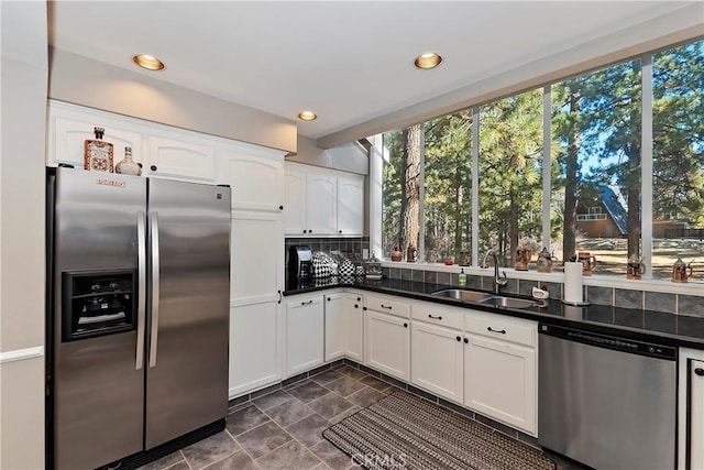 kitchen featuring stainless steel appliances, white cabinetry, sink, and backsplash