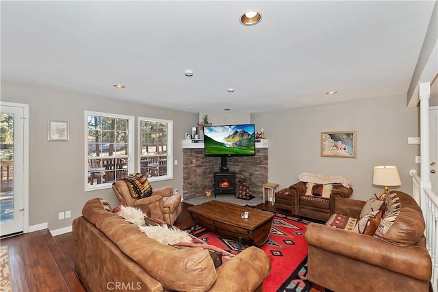 living room featuring decorative columns, wood-type flooring, and a wood stove