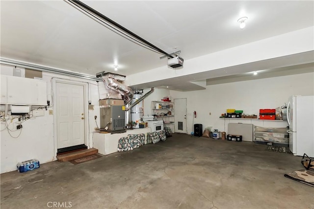 garage featuring heating unit, white fridge, and a garage door opener