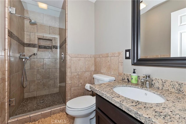 bathroom featuring tile walls, vanity, toilet, and walk in shower