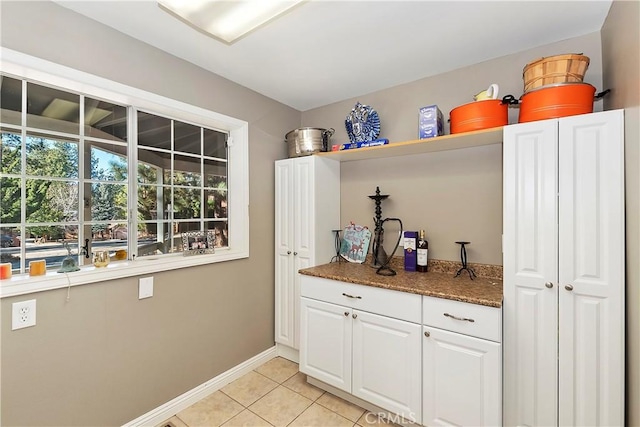 kitchen with white cabinetry, dark stone counters, and light tile patterned floors