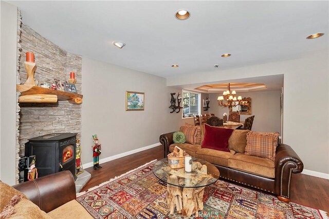 living room featuring a wood stove, dark hardwood / wood-style flooring, and a notable chandelier