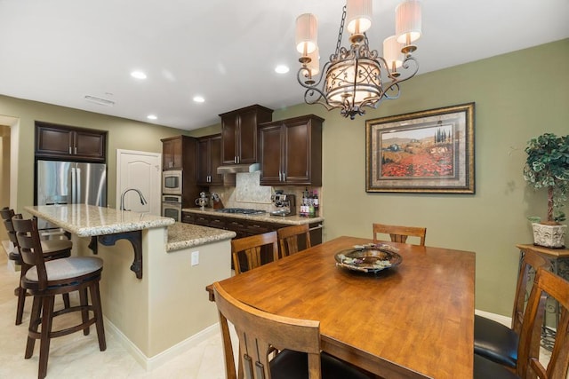 dining space featuring sink, light tile patterned floors, and a chandelier