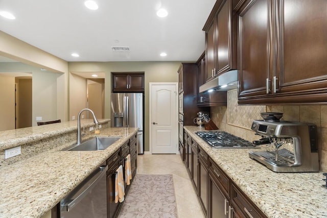 kitchen featuring light stone countertops, appliances with stainless steel finishes, tasteful backsplash, sink, and light tile patterned floors