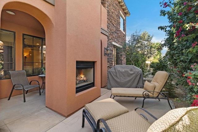 view of patio with an outdoor fireplace and a grill