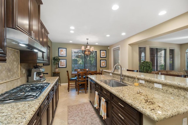 kitchen with a kitchen island with sink, sink, decorative backsplash, appliances with stainless steel finishes, and a chandelier