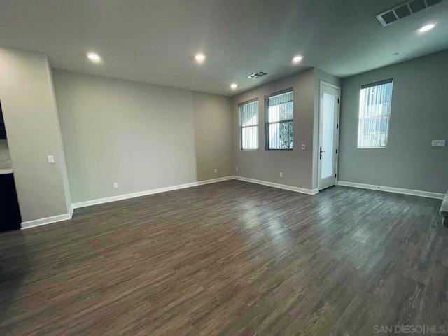 unfurnished living room with a wealth of natural light and dark wood-type flooring