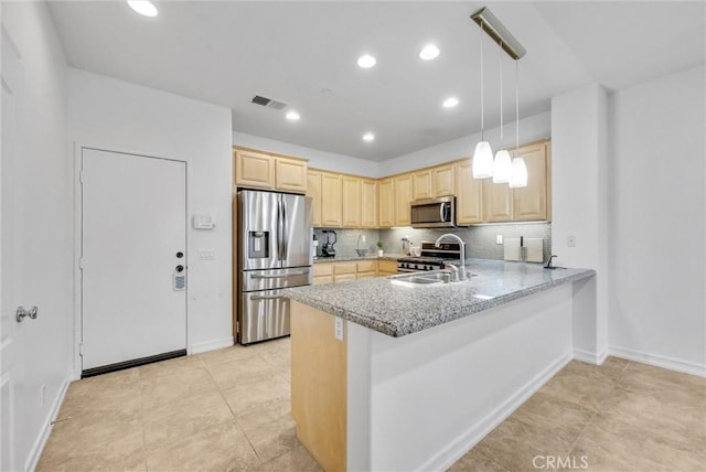 kitchen featuring kitchen peninsula, appliances with stainless steel finishes, tasteful backsplash, sink, and decorative light fixtures