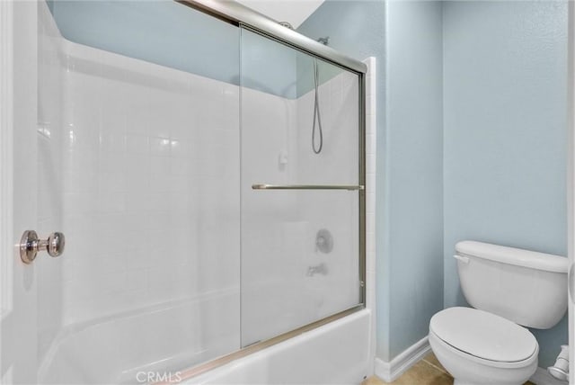 bathroom featuring tile patterned flooring, toilet, and bath / shower combo with glass door