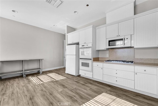 kitchen with white cabinets, wood-type flooring, white appliances, and tasteful backsplash