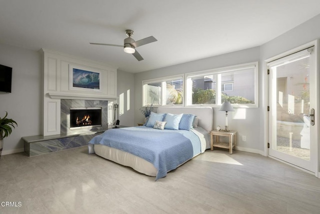 bedroom with access to exterior, a fireplace, and ceiling fan