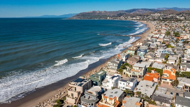 drone / aerial view with a water and mountain view and a view of the beach