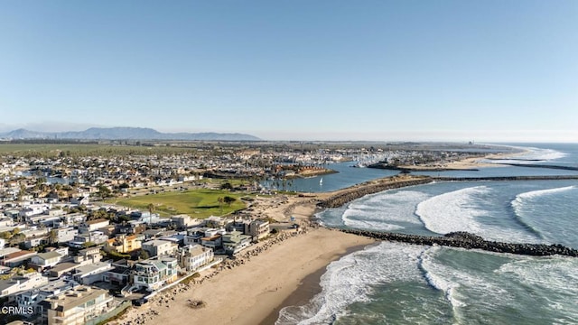 drone / aerial view with a water and mountain view and a view of the beach