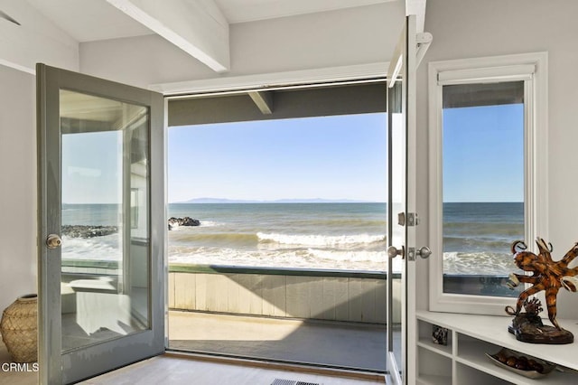 doorway featuring light wood-type flooring, a beach view, and a water view