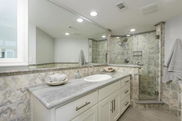 bathroom with tile walls, walk in shower, and vanity