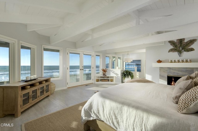 bedroom featuring a fireplace, a water view, french doors, access to exterior, and light hardwood / wood-style flooring