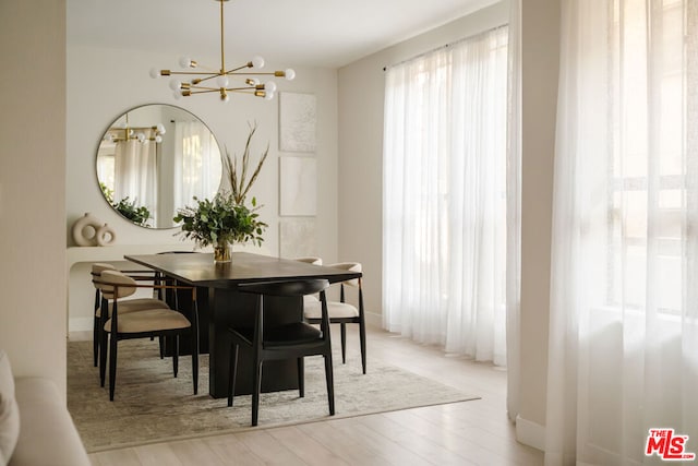 dining room with light wood-type flooring and an inviting chandelier