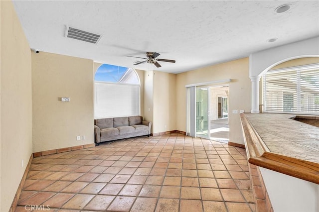 unfurnished living room with decorative columns, ceiling fan, and light tile patterned flooring