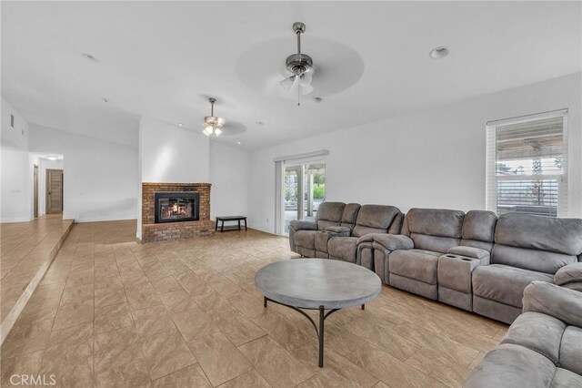 living room featuring ceiling fan, a fireplace, and vaulted ceiling