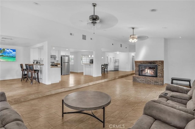 living room with ceiling fan and a brick fireplace