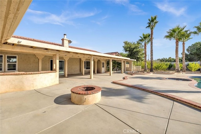 back of property featuring a fire pit and a patio