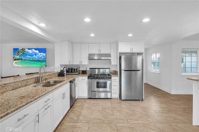 kitchen featuring light stone counters, stainless steel appliances, white cabinetry, and sink