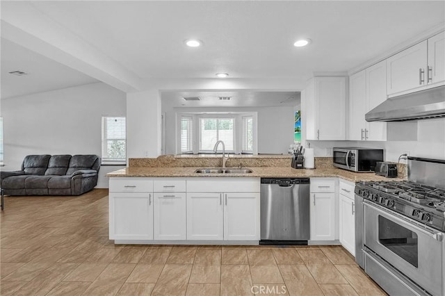 kitchen with light stone counters, sink, white cabinets, and stainless steel appliances