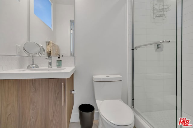 bathroom featuring an enclosed shower, backsplash, vanity, and toilet