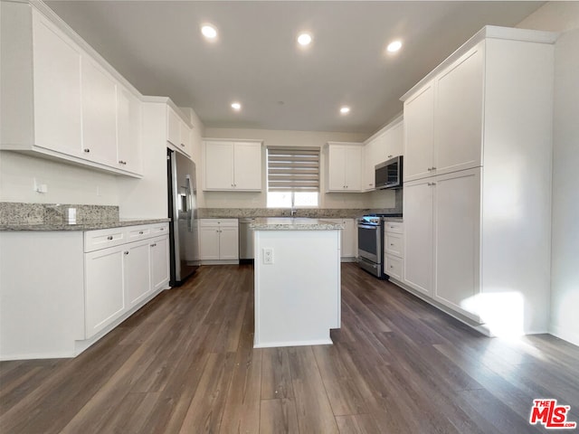 kitchen with dark hardwood / wood-style floors, appliances with stainless steel finishes, white cabinetry, and a kitchen island