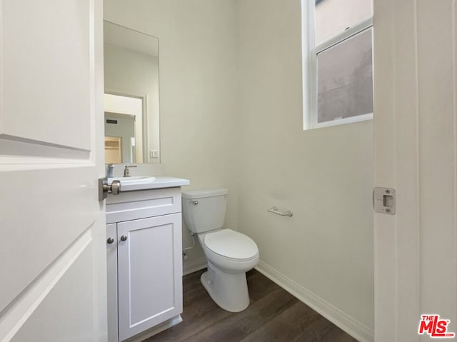 bathroom featuring wood-type flooring, toilet, and vanity