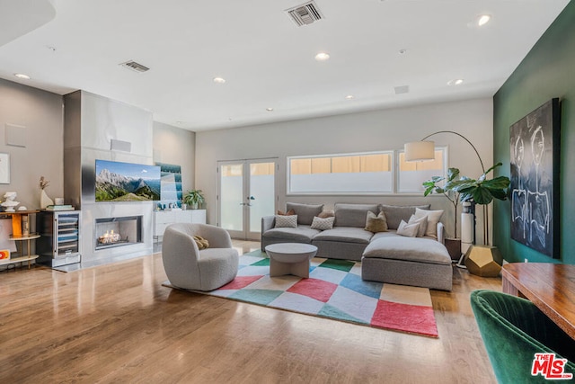 living room with french doors, light hardwood / wood-style floors, and a tiled fireplace