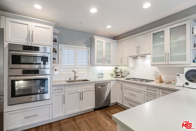 kitchen with appliances with stainless steel finishes, dark hardwood / wood-style floors, white cabinetry, and sink