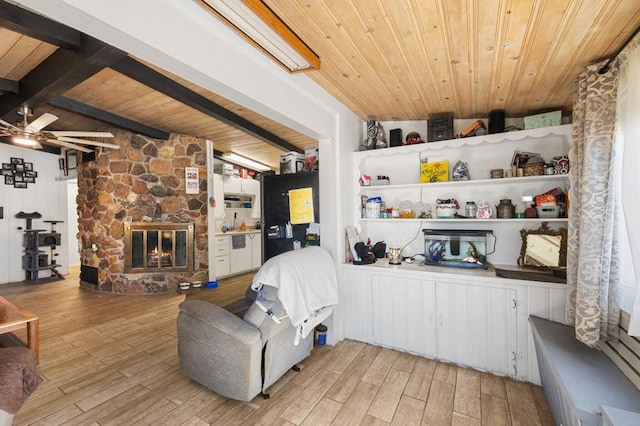 living room featuring wood ceiling, a stone fireplace, ceiling fan, and light hardwood / wood-style floors