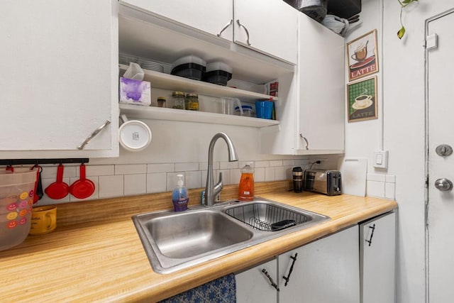 kitchen featuring butcher block counters, decorative backsplash, sink, and white cabinets