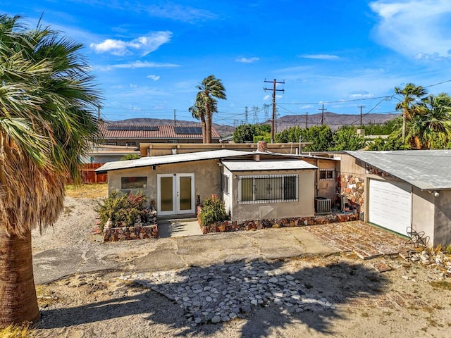 back of property featuring cooling unit, a garage, and french doors