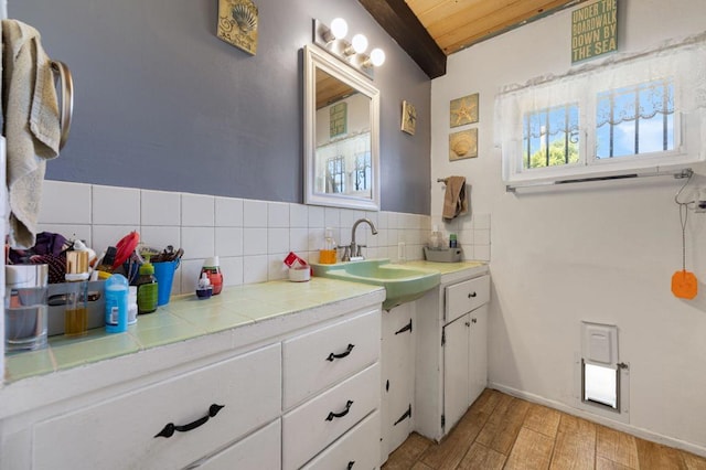 bathroom featuring decorative backsplash, beam ceiling, vanity, and wood ceiling